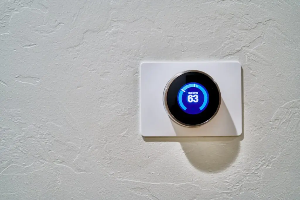 concerned homeowner checking thermostat in cold house during winter - signs you need emergency hvac service