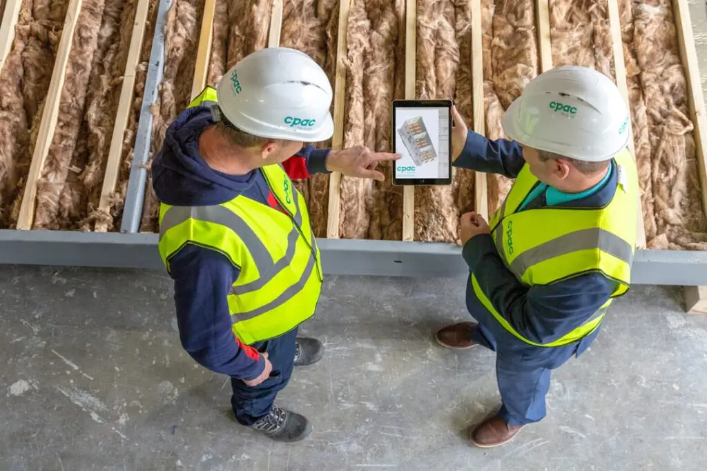 HVAC contractor and homeowner reviewing heat pump rebate options outside a modern home